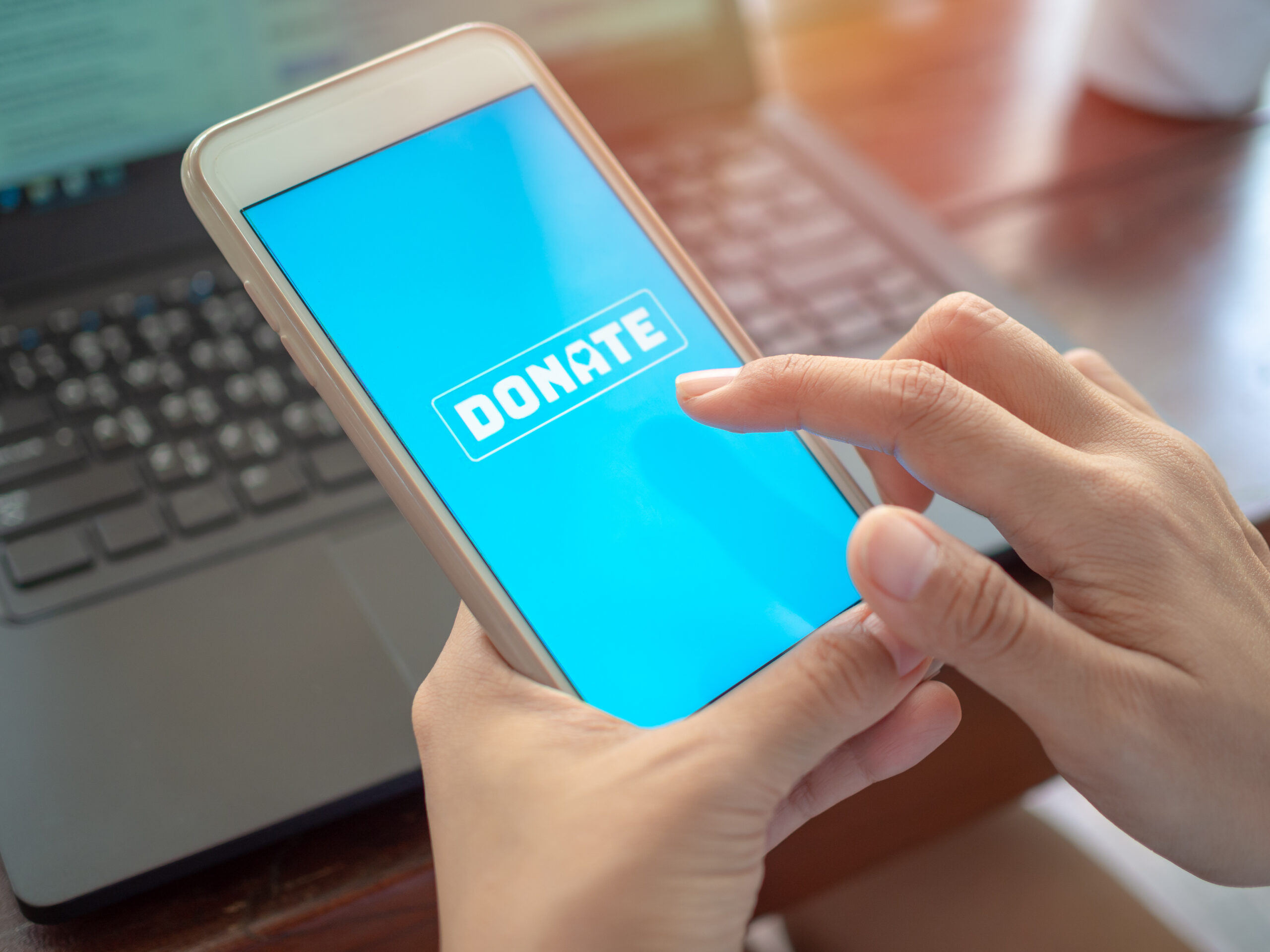 hands holding a mobile phone about to donate online