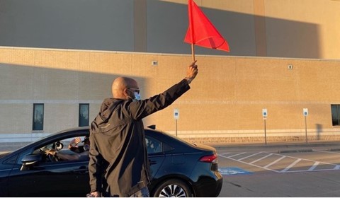 Man waving flag at supply-giving site thanks to cross-country church donation.